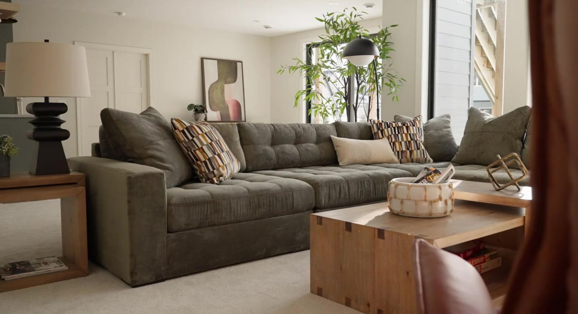 Living room with a green sectional sofa, wooden coffee table, and decorative items.